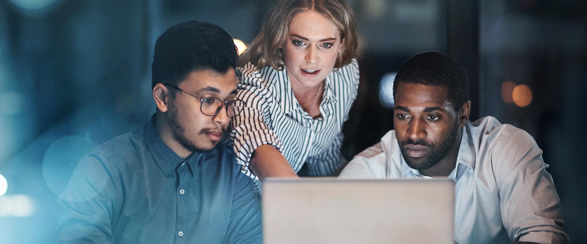 Jeunes gens d'affaires travaillant ensemble sur un portable, tard le soir
