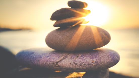 Des pierres en équilibre avec rayons de soleil pour illustrer la santé mentale saine
