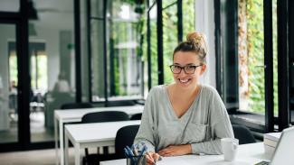 femme souriante assise à son bureau devant son ordinateur