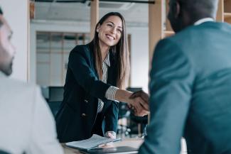 Femme souriante donnant une poignée de main à un homme illustrant son embauche