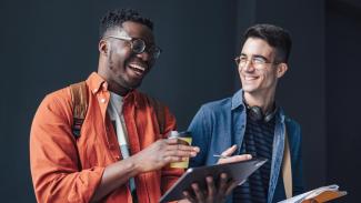 Deux étudiants souriants côte à côte regardant une tablette