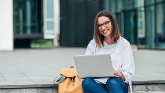 Femme souriante assise avec portable et sac
