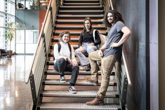 Étudiantes et étudiants souriants assis ensemble dans un escalier sur le campus de Québec