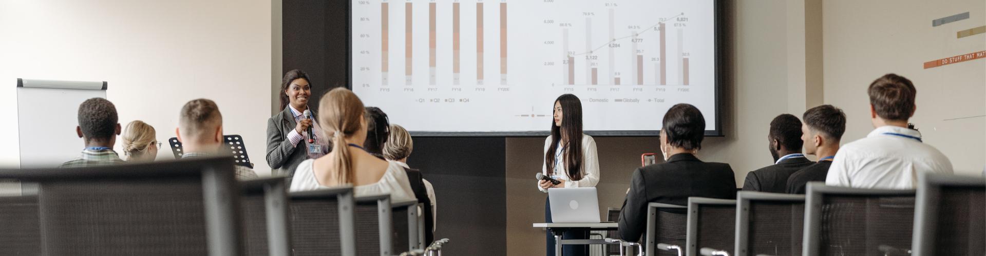 Présentation de deux femmes sur l'évaluation devant un groupe de gens assis.